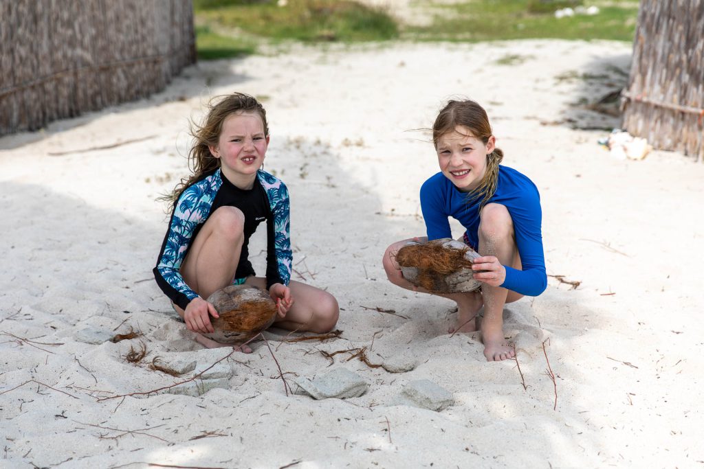 Lia und Milena versuchen eine Kokosnuss zu öffnen