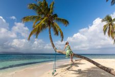 Palme mit Model am Strand von Nubesidup, San Blas, Panama